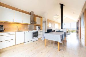 Una cocina con gabinetes blancos y una mesa con sillas. en 712-Hvide-Sande-Slusen-12, en Hvide Sande