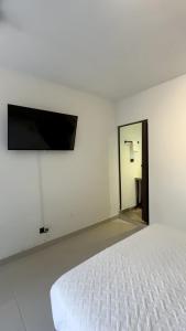 a bedroom with a white bed and a flat screen tv at Hotel Boutique Albania in Otanche +32 photos