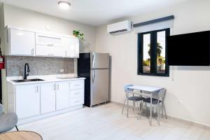 uma cozinha com armários brancos, uma mesa e um frigorífico em Fully Renovated Beachside with Oceanview 1 Bedroom Unit 5 em Dorado