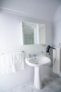 ein weißes Badezimmer mit einem Waschbecken und einem Spiegel in der Unterkunft Micca House in Ostuni