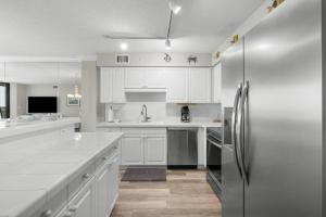 ポーリーズ・アイランドにあるSeaside Paradise 3BR Condo Steps from the Beachの白いキャビネットとステンレス製の冷蔵庫を備えたキッチン