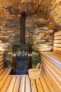a wood stove sitting in a sauna with a basket at Warsztat SAUNA&JACUZZI in Poronin