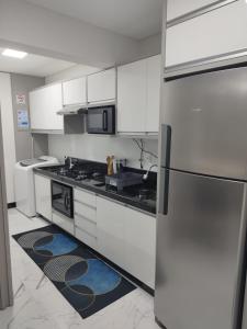 a kitchen with white cabinets and a stainless steel refrigerator at Apartamento temporada - Meia Praia in Itapema