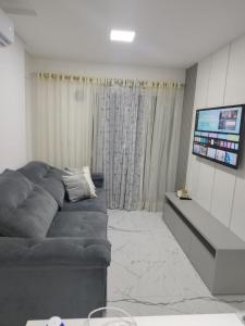 a living room with a couch and a flat screen tv at Apartamento temporada - Meia Praia in Itapema
