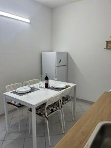 a white table with wine glasses and a refrigerator at Casa Ariel in Avola