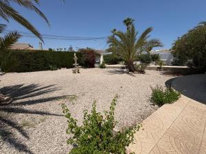 a gravel courtyard with trees and a fountain in a yard at Ideal pool chalet WBR in La Mata