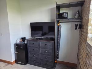 a bedroom with a dresser with a tv and a black at The Mill Hotel in Fergus Falls