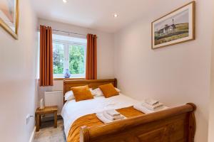 a bedroom with a wooden bed with orange pillows at Premium 2 Bed Apt 1st floor sleeps 4 adults in Oban town in Oban
