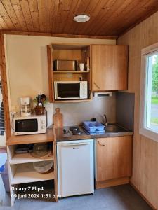 a small kitchen with a white refrigerator and microwave at Camping La Chapelle in La Chapelle-Taillefert
