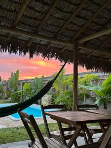 a hammock and a table and chairs under a straw umbrella at Morada do Vento in Guriú