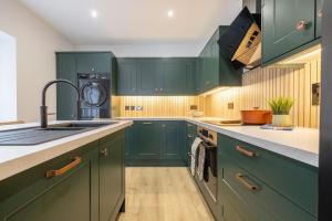 a kitchen with green cabinets and a washing machine at Large house in centre of Portrush with free parking x 2 cars in Portrush