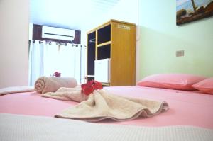 a bedroom with a pink bed with towels on it at Pousada Raio de Sol in Fernando de Noronha