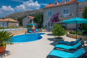a pool with chairs and umbrellas in front of a house at Villa Ida in Dubrovnik