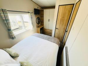 a small bedroom with a bed and a window at 2 Bedroom Caravan FF17, Fairway, Sandown, Isle of Wight in Isle of Wight