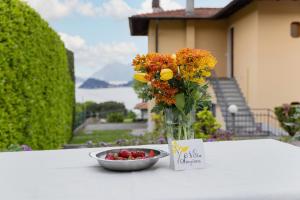 a vase filled with flowers next to a bowl of berries at Villa Sanziana in Menaggio