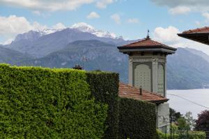 a building with a tower with a mountain in the background at Villa Sanziana in Menaggio