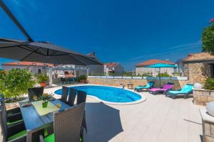 a patio with a pool and chairs and an umbrella at Villa Ida in Dubrovnik
