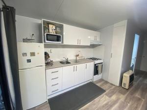 a kitchen with white cabinets and a sink and a microwave at Mountain Escape in Wentworth Falls