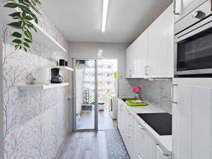 una cucina con armadi bianchi e carta da parati floreale di Cristimar Roja Beach a Los Cristianos