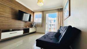 a living room with a couch and a flat screen tv at Descanso cond edifício tropical B in Maceió