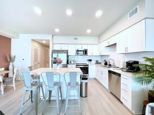 Una cocina con gabinetes blancos y una mesa y sillas. en Sea Glass 311 2BR on the Beach, en Gulf Shores