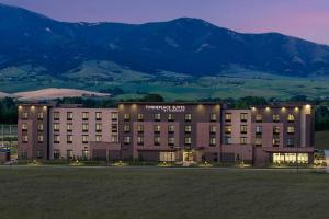 a hotel building with a mountain in the background at TownePlace Suites by Marriott Bozeman West in Bozeman