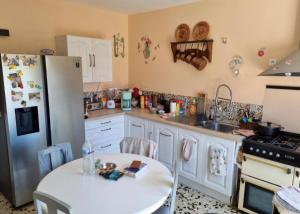a kitchen with a white table and a refrigerator at L'arche de noe in Audinghen