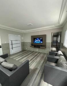 a living room with two couches and a flat screen tv at Casa para família com piscina in Guarujá +1 photo