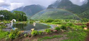a rainbow over a pool of water with mountains in the background at Casa Oliver, tra la Calanca e i castelli di Bellinzona in Grono +2 photos