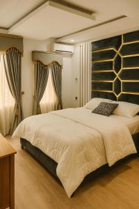 a bedroom with a large white bed and curtains at SEATWORK APARTMENT Enugu in Enugu Airport