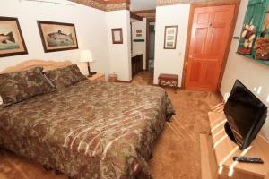 ein Schlafzimmer mit einem Bett und einem Schreibtisch mit einem Fernseher in der Unterkunft Mountainback #34, Corner in Mammoth Lakes