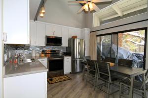 Una cocina con gabinetes blancos y una mesa con sillas. en Sierra Park Villas #93, en Mammoth Lakes