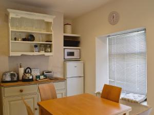 Una cocina con una mesa y un refrigerador blanco. en Sundowners, en Calstock