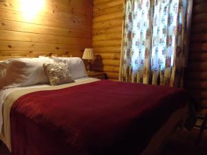 a bedroom with a bed with wooden walls and curtains at Cajun Cedar Log Cottages in Margaree Forks