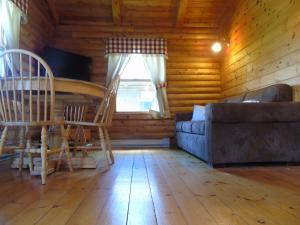 
a living room filled with furniture and a window at Cajun Cedar Log Cottages in Margaree Forks
