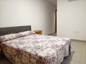 ein Schlafzimmer mit einem Bett mit geblümter Decke in der Unterkunft Apartamento Costacabana in Almería