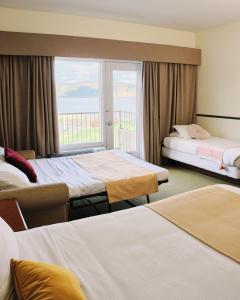 a hotel room with three beds and a window at BATTURES Hotel Fjord Saguenay in La Baie