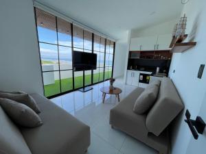 a living room with a couch and a large window at GLAMSUITE FRENTE AL MAR con HIDRO in Montañita