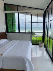 a bedroom with a large white bed and large windows at GLAMSUITE FRENTE AL MAR con HIDRO in Montañita