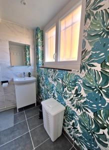 a bathroom with a toilet and a sink with a leafy wallpaper at Gite Bernard Lafon in Castillon-la-Bataille