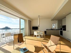 トレブールダンにあるLE TAUREAU T3 Trebeurden acces plage piscine et vue merのテーブルと椅子、キッチンのあるリビングルーム