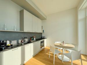 Una cocina con gabinetes blancos y una mesa y sillas. en Le castel T2 piscine et vue mer plage, en Bonne Nouvelle