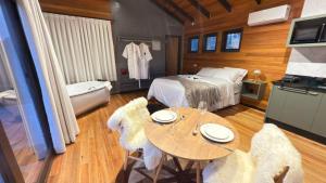a bedroom with a bed and a table and chairs at Vila Chamonix - Chalé Merlot in Urubici
