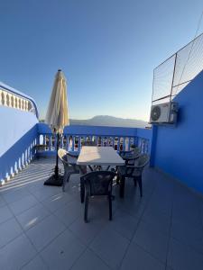 ein Balkon mit Tischen, Stühlen und einem Sonnenschirm in der Unterkunft Ammour Apartment in Chefchaouen