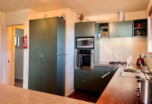 a kitchen with green cabinets and a refrigerator at Pukeko Palace - Lake Tekapo in Lake Tekapo