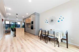 a kitchen and dining room with a table and chairs at Harborlight--Modern 2 Bedroom Townhouse in Hobsonville in Auckland