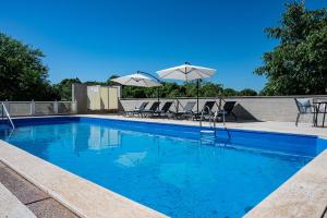 une piscine bleue avec des chaises et des parasols dans l'établissement Family friendly house with a swimming pool Krnica, Marcana - 24375, à Krnica