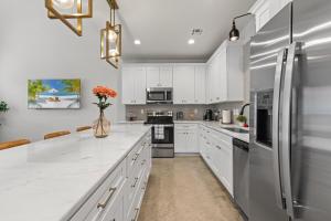 a kitchen with white cabinets and a refrigerator at Voodoo House KING Bed Garage Fast WiFi 65 Tv in Lafayette