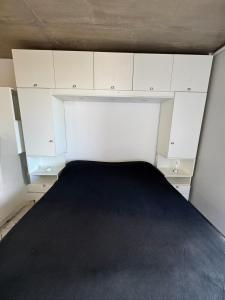 a small bedroom with white cabinets and a black bed at Alem Apartamento in La Porteña