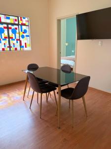 a dining room with a glass table and chairs at Beautiful Loft in the heart of colonia Americana in Guadalajara +3 photos